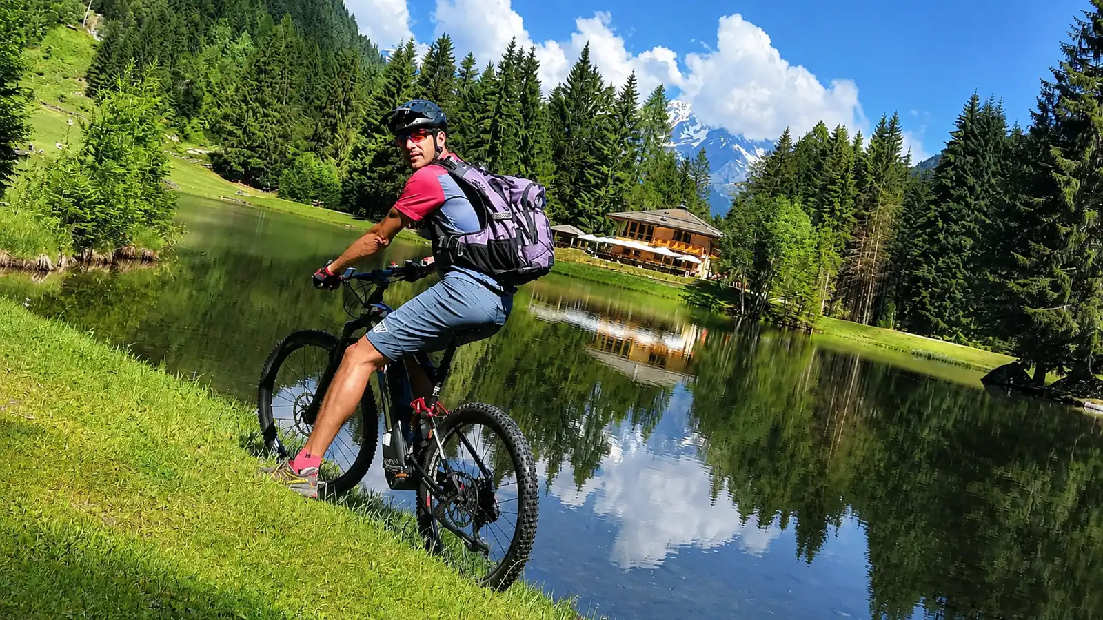 Un biker in mountain bike accanto a un laghetto alpino della Val di Sole